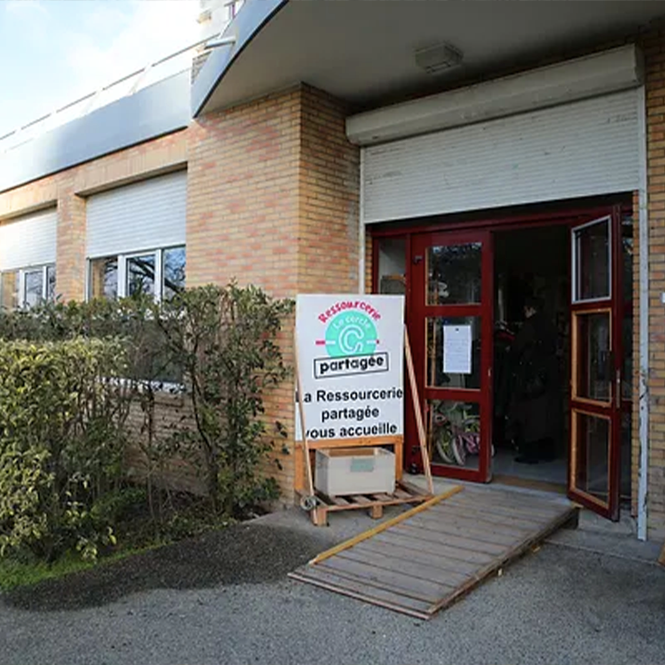 Image d'extérieur de la Ressourcerie Partagée, kakémono devant la porte d'entrée du lieu