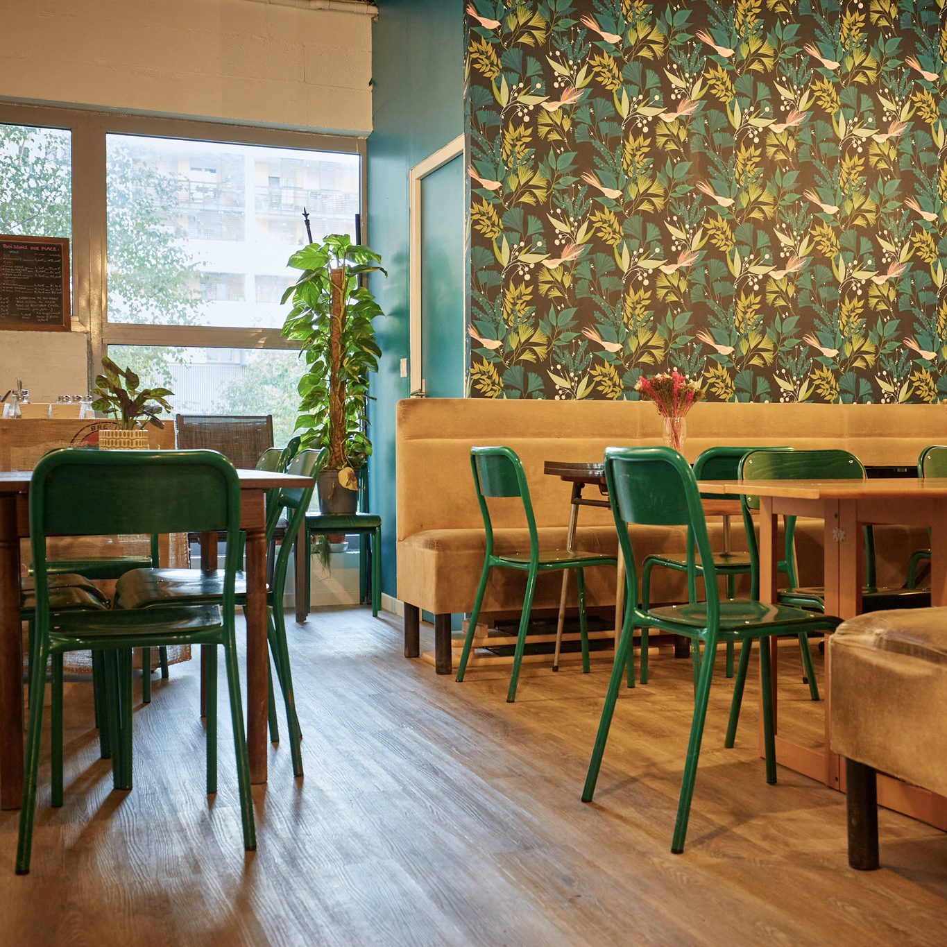 Image d'intérieur de La Récolte Citadine, chaises vertes, sol en bois, mur en papier peint